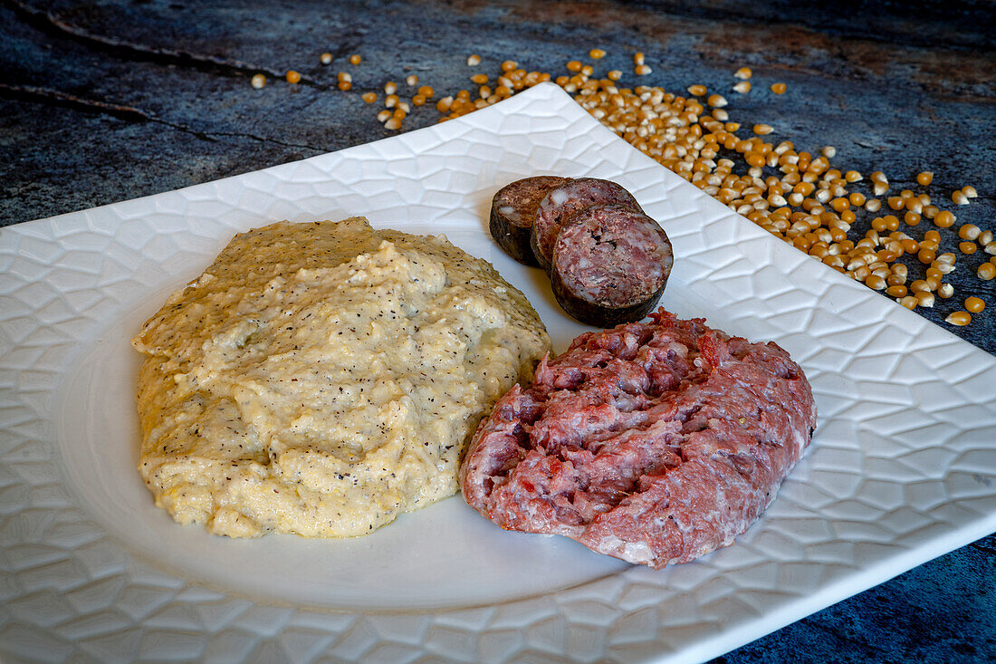 Dish of polenta taragna with sausage and mortadella, traditional food of Italy