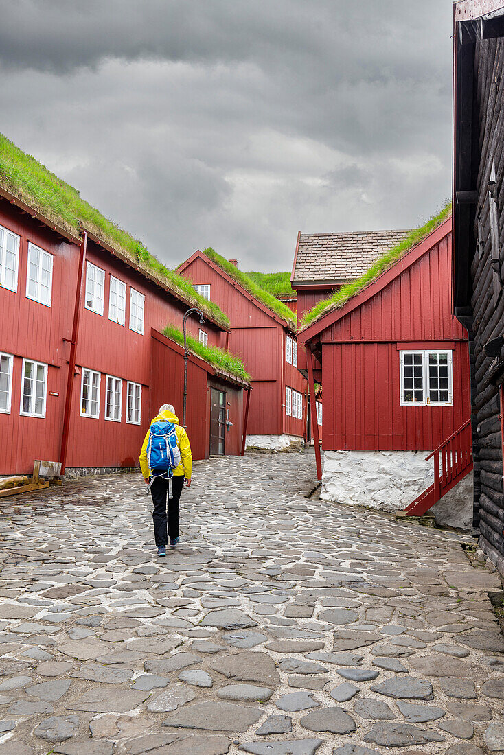 Tourist geht durch die engen Gassen des hystorischen Stadtzentrums von Tinganes, Torshavn, Streymoy Insel, Färöer Inseln, Dänemark, Europa