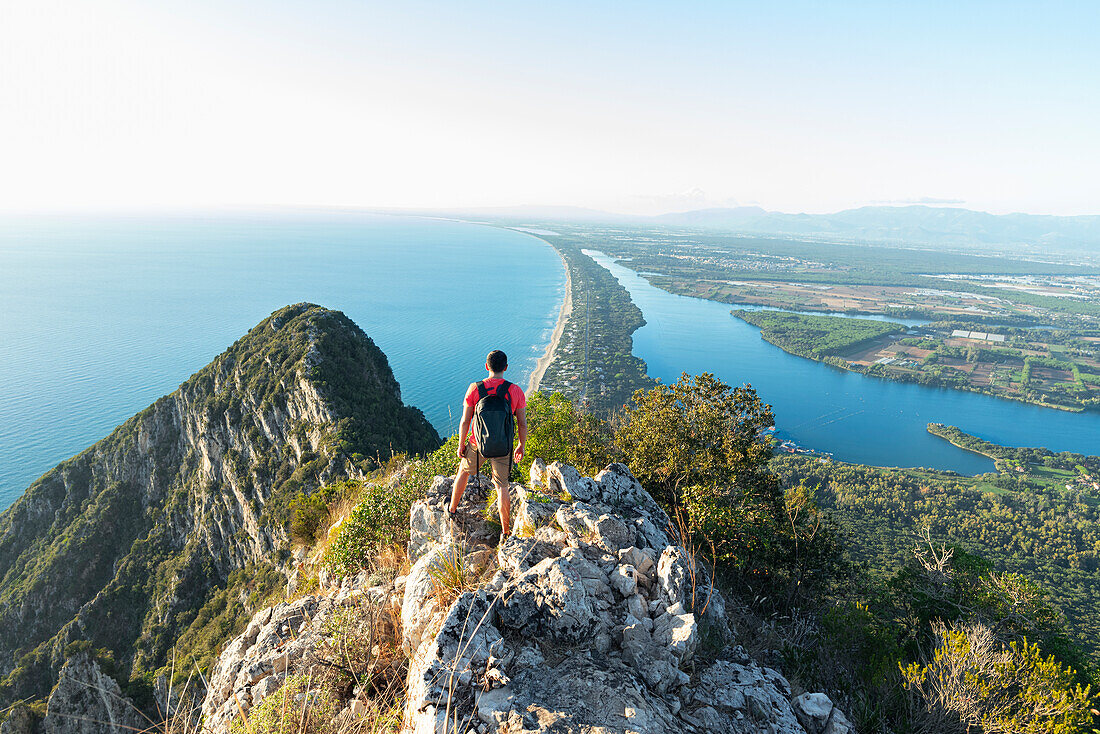 Rear view of a hiker admiring Paola lake and Sabaudia's beach on his route to the peak of Circeo mountain, San Felice Circeo, Circeo National Park, Pontine flats, Latina province, Latium, Central Italy, Italy, Southern Europe, Europe