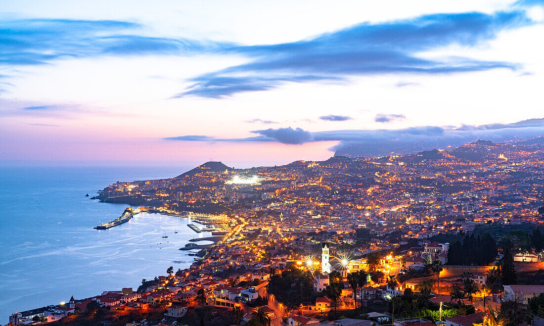 Blick von oben auf die Stadt Funchal und die Bucht in der Abenddämmerung von Sao Goncalo, Insel Madeira, Portugal