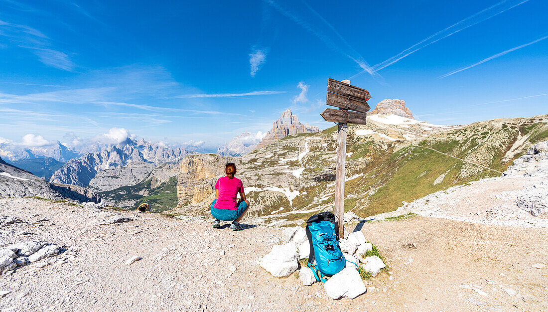 Hiker woman admiring mountains from Oberbachernjoch/Passo Fiscalino in summer, Sesto Dolomites, South Tyrol, Italy