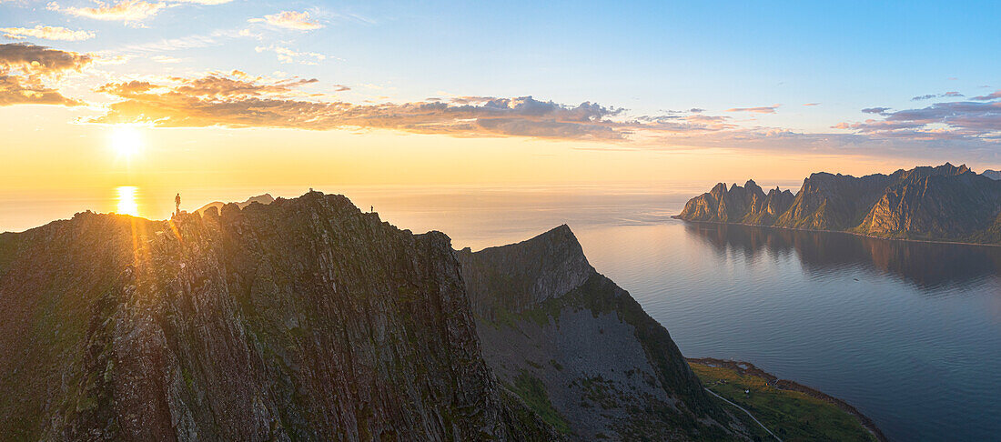 Silhouette of man contemplating sunset from the rocky peak of Husfjellet mountain, Senja, Troms county, Norway