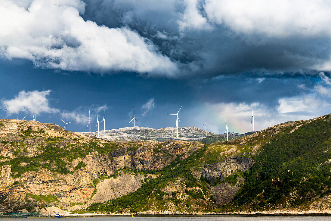 Wind farm of white turbines on rocky coastline, Troms county, Norway