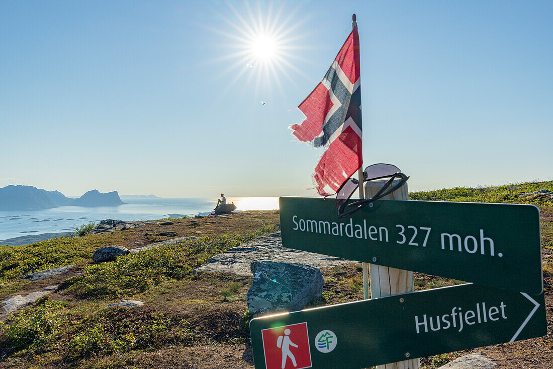 Woman looking at the fjord sitting on rocks on the hike to Husfjellet mountain, Senja island, Troms county, Norway