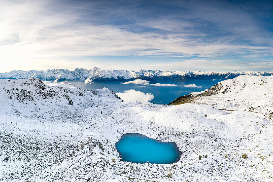 Aerial view of the Orobie Alps mountain range covered with snow and frozen Rogneda lake, Rhaetian Alps, Lombardy, Italy