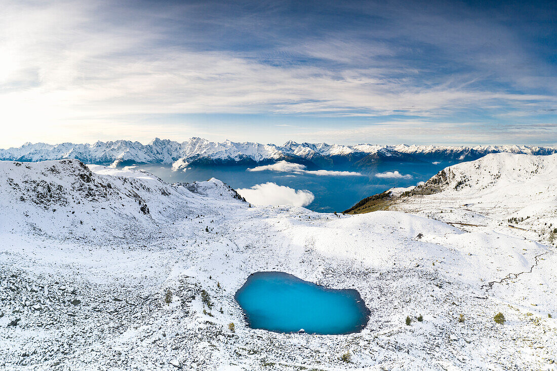 Luftaufnahme der schneebedeckten Orobie-Alpen und des zugefrorenen Rogneda-Sees, Rätische Alpen, Lombardei, Italien