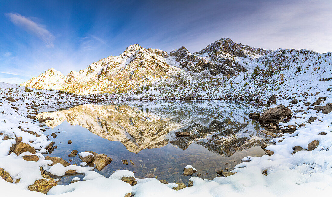 Autumn sunrise over majestic mountains covered with snow reflected in lake Rogneda, Rhaetian Alps, Sondrio, Lombardy, Italy