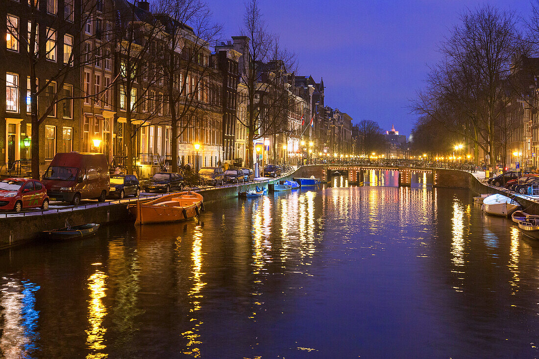 Lights of traditional houses reflected in the canal at dusk, Amsterdam, North Holland, The Netherlands