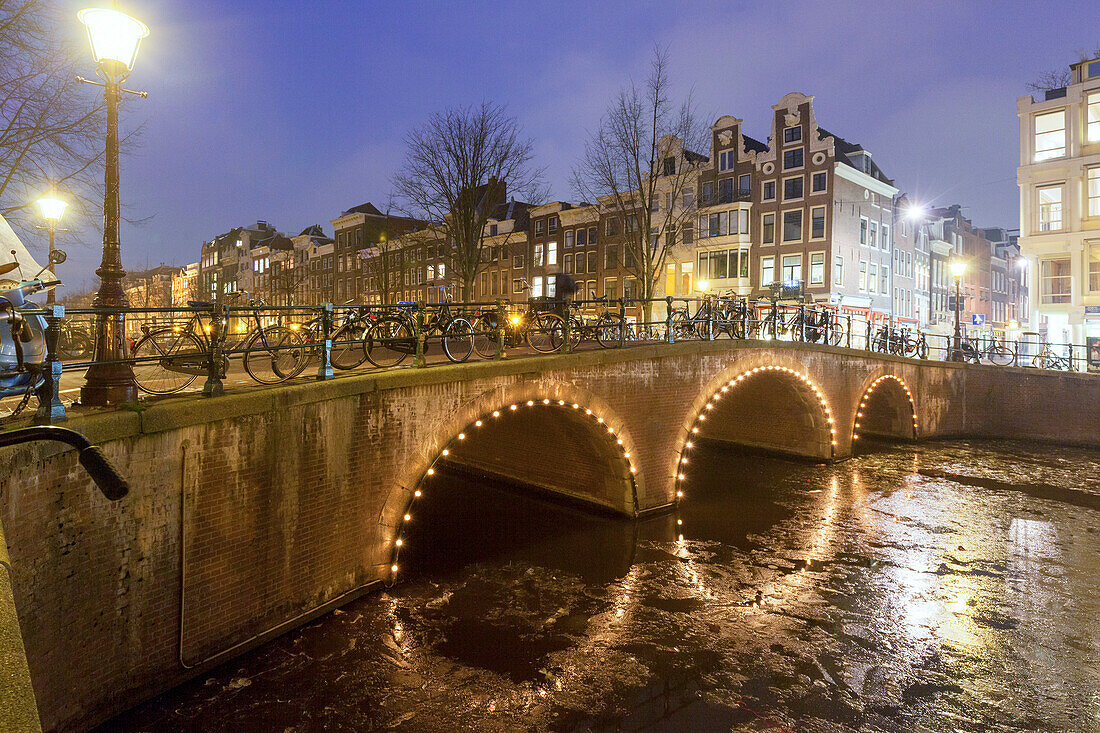 Lights of the old lanterns reflected in the frozen Keizersgracht canal in winter, Amsterdam, North Holland, The Netherlands