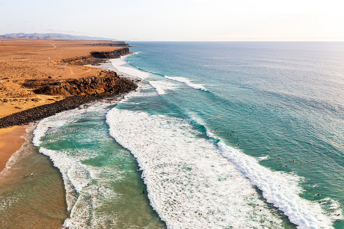 Aerial view of surfers riding the ocean waves at El Cotillo beach, Fuerteventura, Canary Islands, Spain