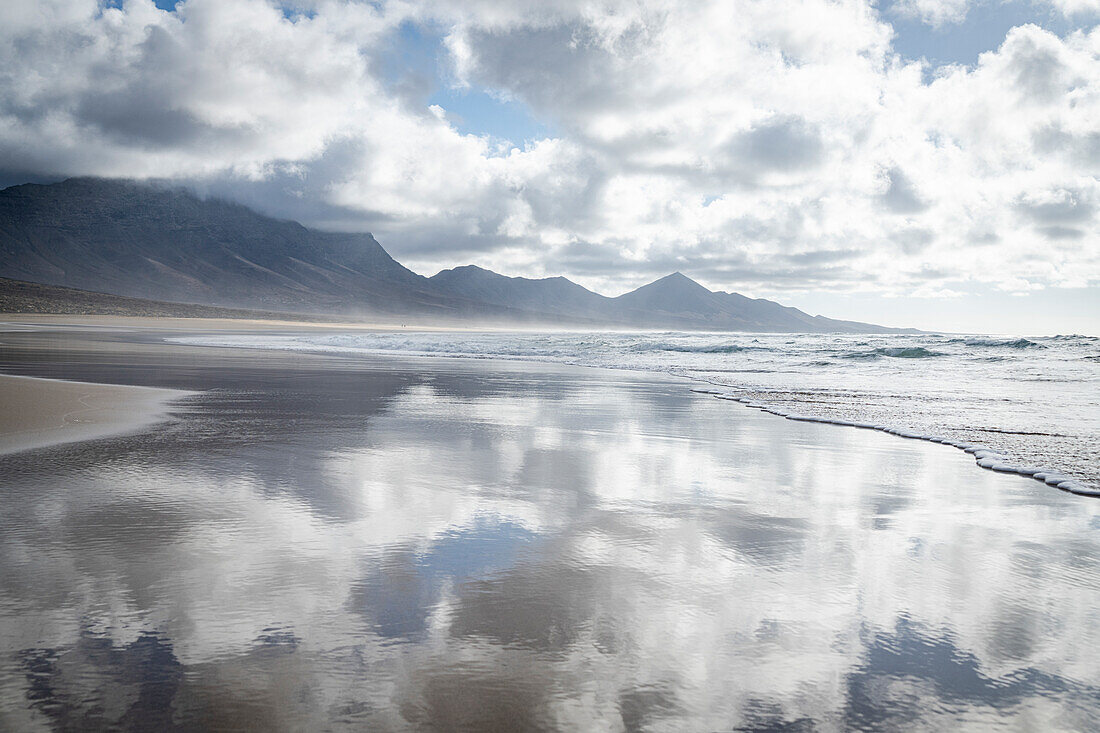 Bewölkter Himmel bei Sonnenuntergang, der sich im Meer spiegelt, Strand von Cofete, Naturpark Jandia, Fuerteventura, Kanarische Inseln, Spanien