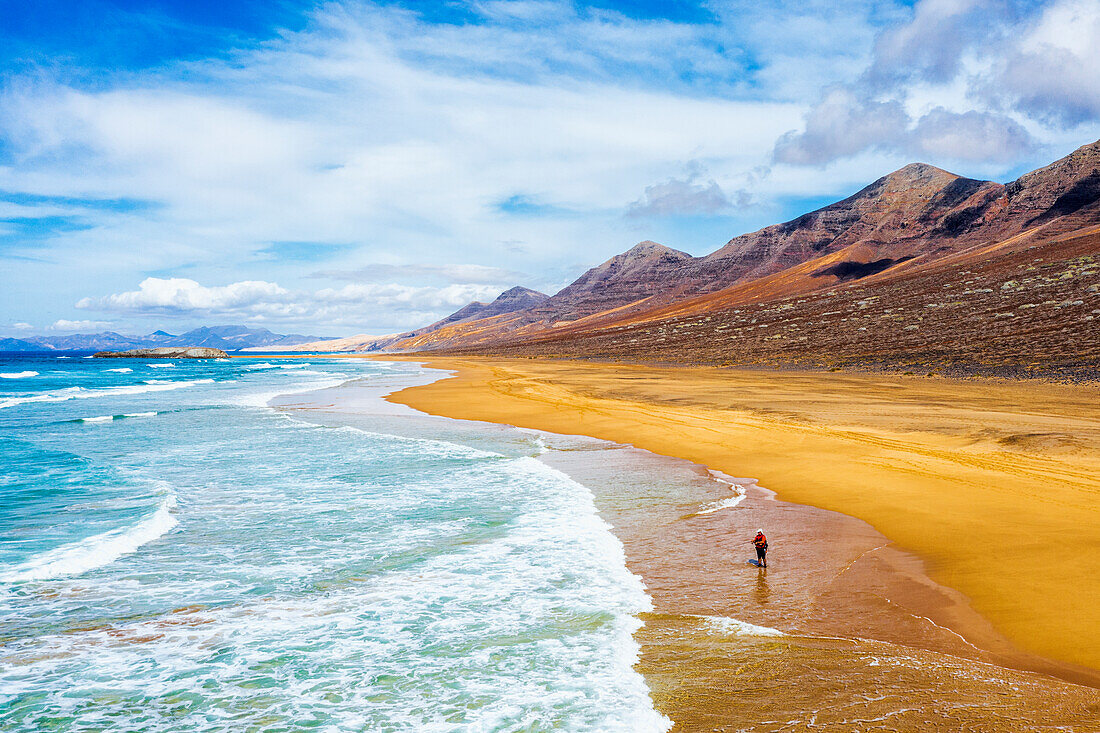 Einsamer Fischer am Strand von Cofete, umspült von den Wellen des Meeres, Naturpark Jandia, Fuerteventura, Kanarische Inseln, Spanien