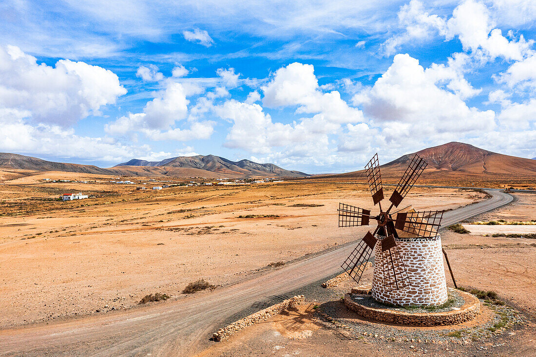 Empty desert road passing by the old stone windmill, Tefia, Fuerteventura, Canary Islands, Spain