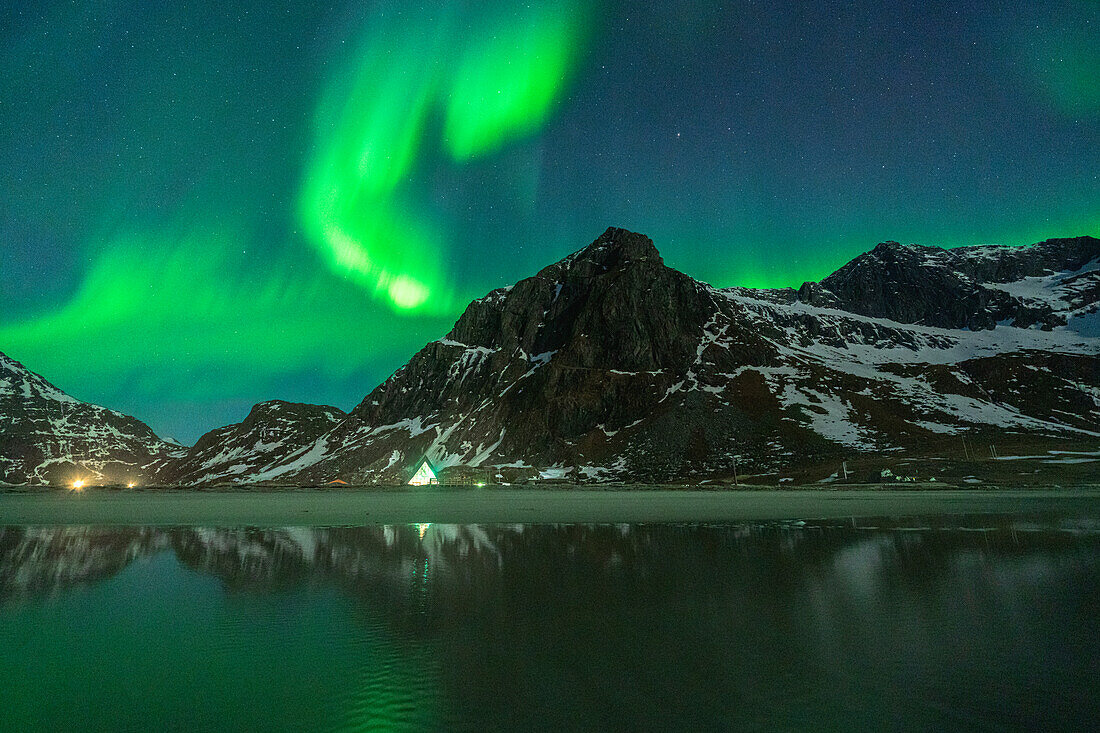 Bright night sky with Northern Lights over mountains and Skagsanden beach, Flakstad, Lofoten Islands, Norway