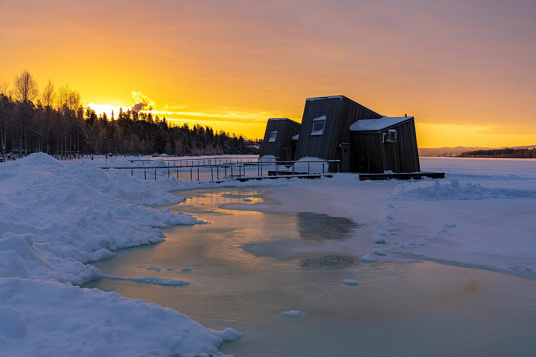Sonnenaufgang über der Holzhütte in der gefrorenen Landschaft, Zimmer des luxuriösen Arctic Bath Spa Hotels, Harads, Lappland, Schweden
