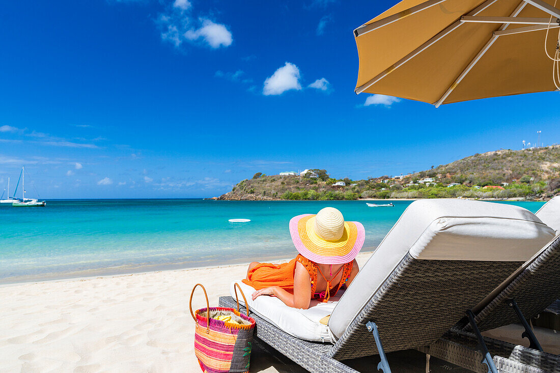 Frau bewundert das Meer auf einer Sonnenliege am weißen Sandstrand, Carlisle Bay, Antigua, Leeward Islands, Karibik, Westindische Inseln