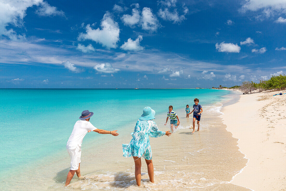 Glückliche Familie mit drei Kindern beim Spielen an einem tropischen Strand im Sommer, Barbuda, Antigua & Barbuda, Karibik, Westindien