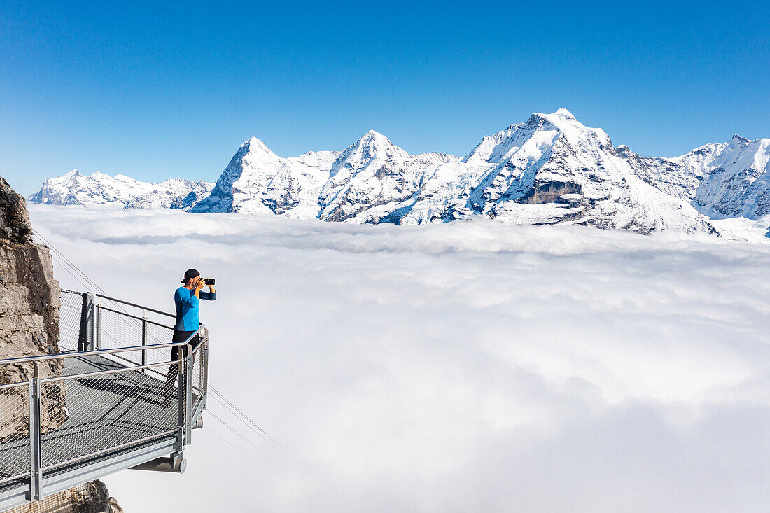 Fotograf geniesst den Blick auf die schneebedeckten Gipfel von Eiger und Mönch vom Skywalk, Murren Birg, Jungfrau Region, Bern, Schweiz
