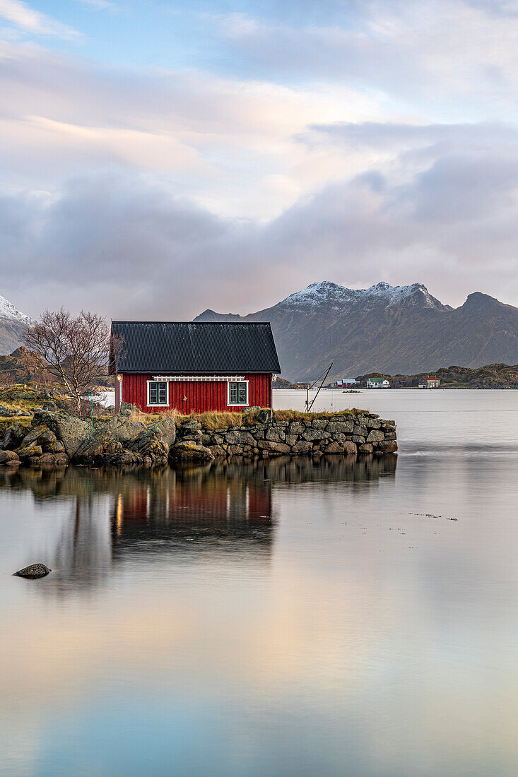 Sunrise over traditional red Rorbu overlooking the fjord, Ballstad, Vestvagoy, Nordland county, Lofoten Islands, Norway