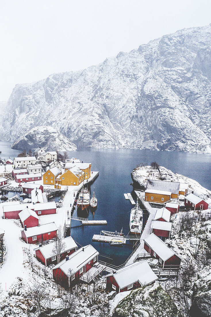 Luftaufnahme des Fischerdorfs Nusfjord und des Hafens nach einem Winterschneefall, Bezirk Nordland, Lofoten, Norwegen