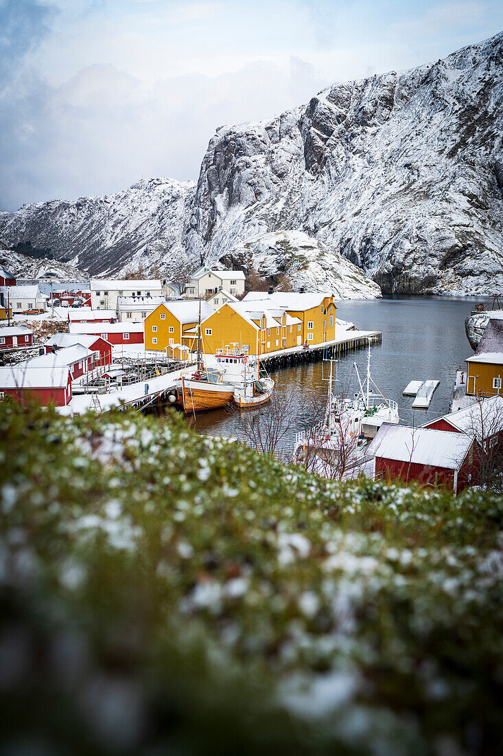 Kleines Fischerdorf und Hafen im Winter mit Schnee bedeckt, Nusfjord, Landkreis Nordland, Lofoten-Inseln, Norwegen