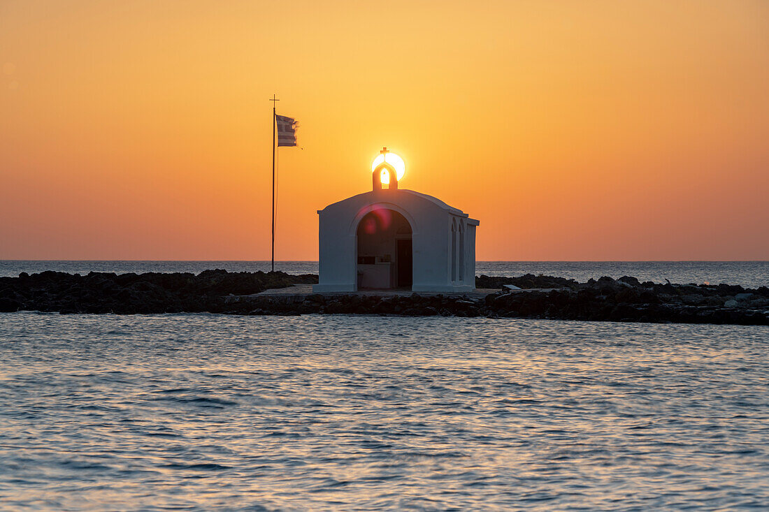 Sun rising over the iconic Greek chapel overlooking the rough sea, Georgioupolis, Crete island, Greece