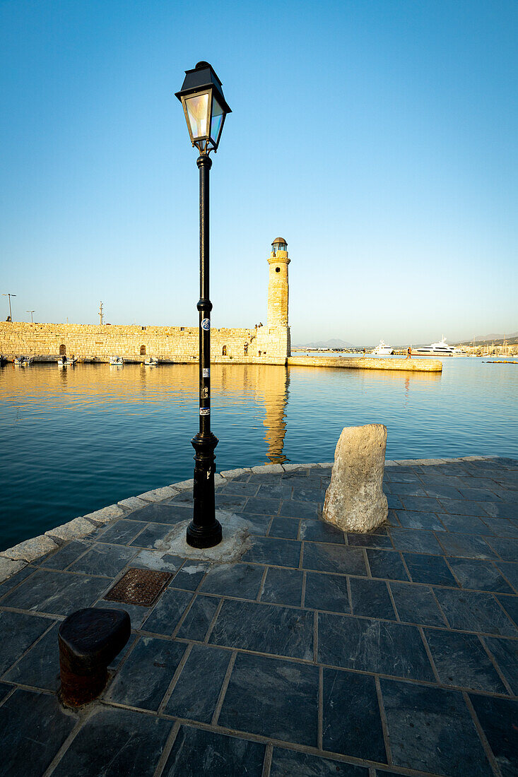 Sunset over the old lighthouse in the Venetian harbour of Rethymno, Crete island, Greece