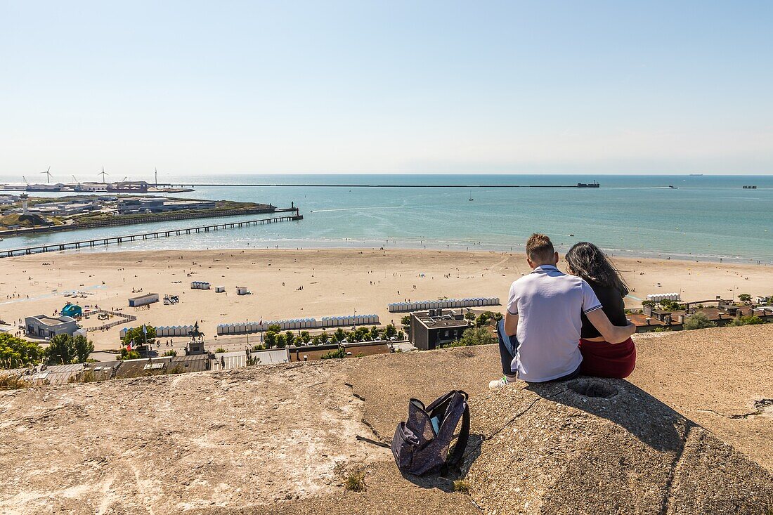 Young couple sitting over the sea on the beach of boulogne sur mer, (62) pas-de-calais, france