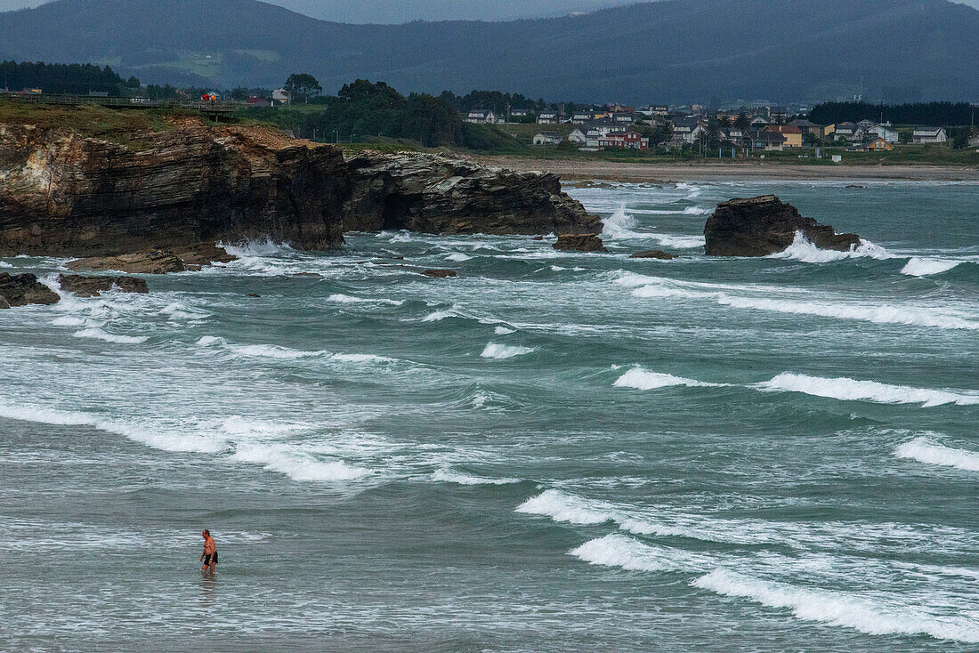 As Catedrais or Las Catedrales Beach by sunset, in Ribadeo, Lugo. Galicia, Spain. Tourists by a stone arch at Beach of the Cathedrals Natural Monument at Ribadeo municipality, Lugo province, Galicia, Spain, Europe