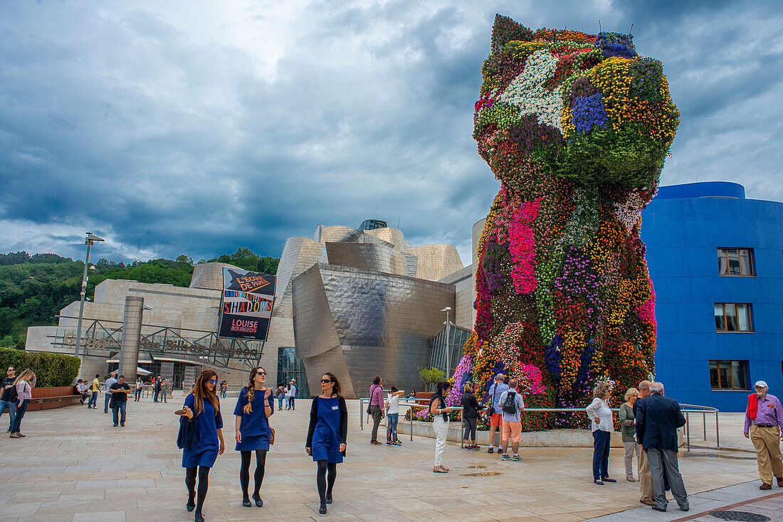 Jeff Koons' Skulptur Puppy vor dem Guggenheim Museum, Bilbao, Spanien. Der Eingang des Guggenheim-Museums in Bilbao spiegelt sich im Fluss Nervion, Bilbao, Baskenland, Spanien