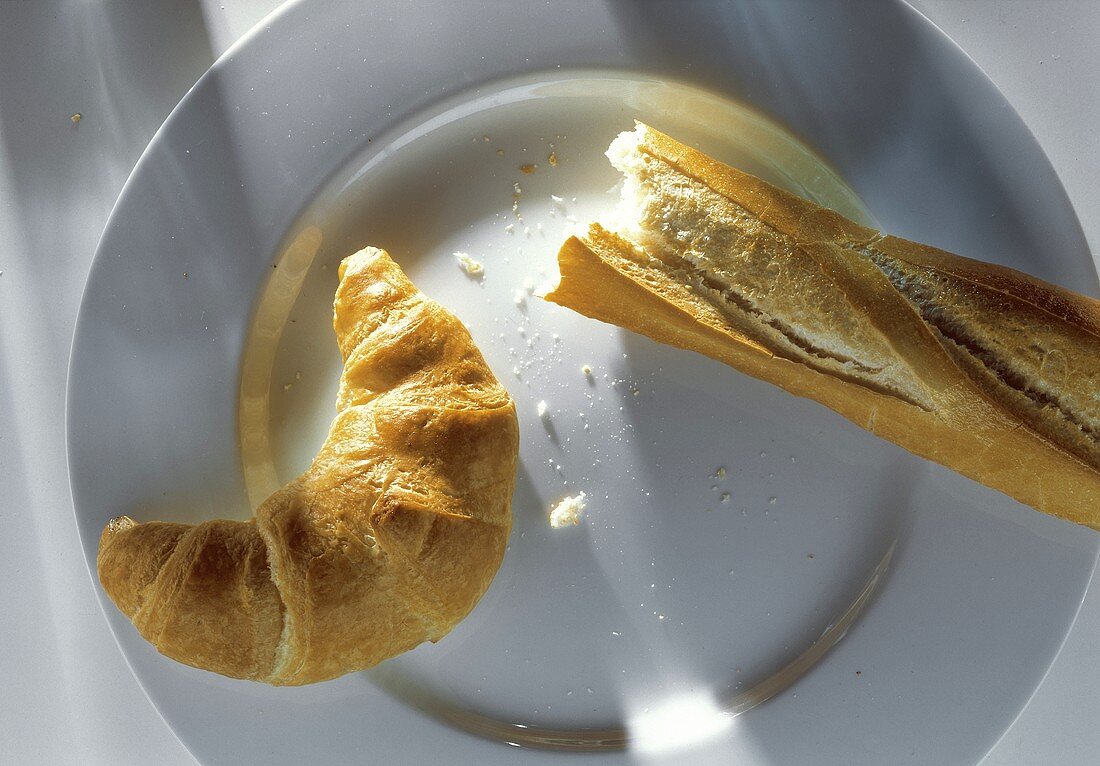 A Croissant and Italian Bread on a Plate; Overhead