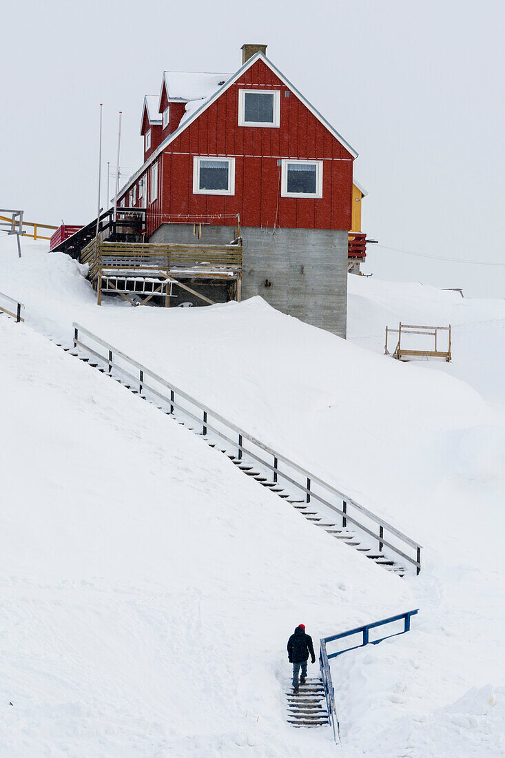 A stairway to a colorful house in a snowy landscape. Ilulissat, Greenland.
