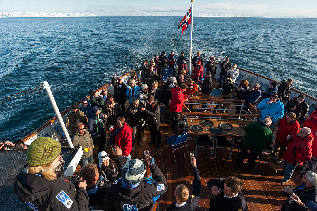 Cruise tourists celebrate crossing 80 degrees North near the island of Moffen. Moffen, Svalbard, Norway.