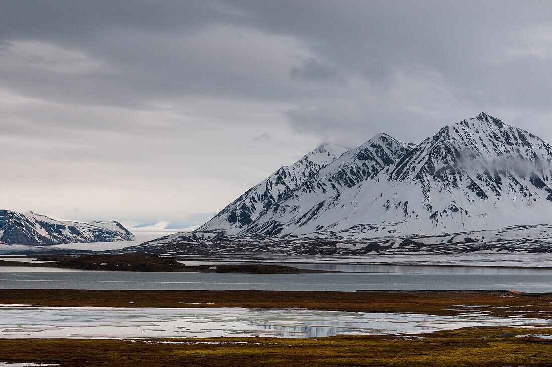 A scenic view of mountains and arctic waters at Ny-Alesund on Kongsfjorden. Ny-Alesund, Kongsfjorden Spitsbergen Island, Svalbard, Norway.