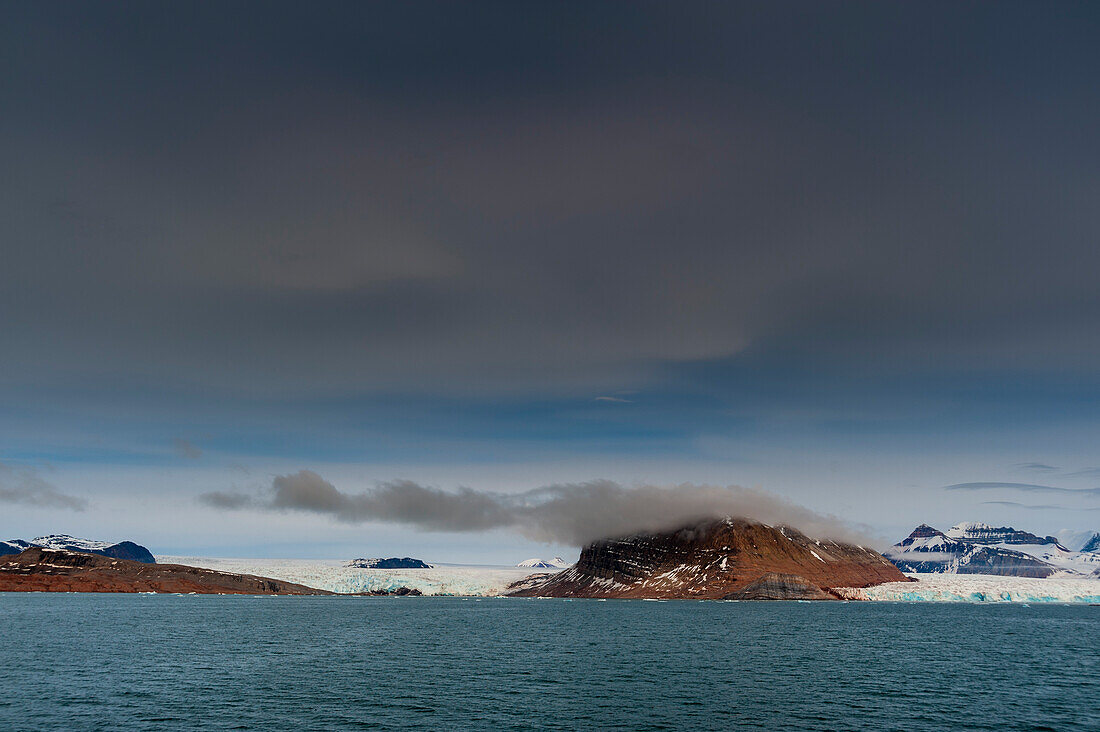 Cloud cover above ice streaked mountains bordering Kongsfjorden near Ny-Alesund. Kongsfjorden, Spitsbergen Island, Svalbard, Norway.