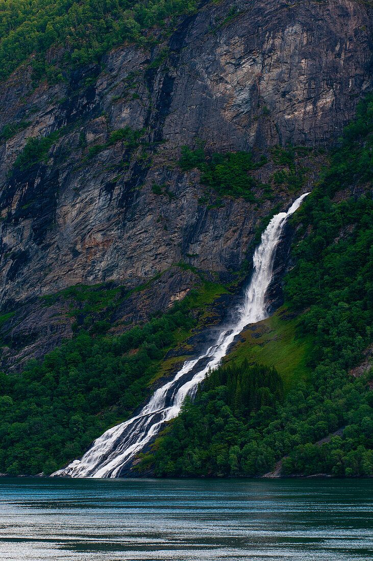 A waterfall cascades into Geirangerfjord. Geirangerfjord, Norway.