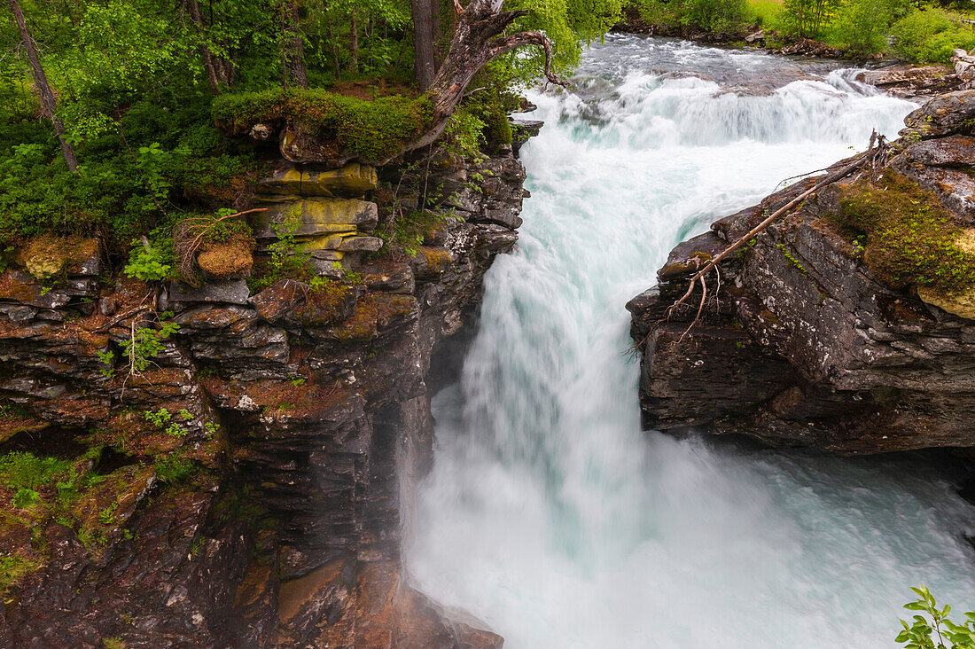 Ein Wasserfall stürzt an Felsvorsprüngen in der Nähe der Straße Trollstigen vorbei. In der Nähe von Trollstigen, Rauma, Norwegen.