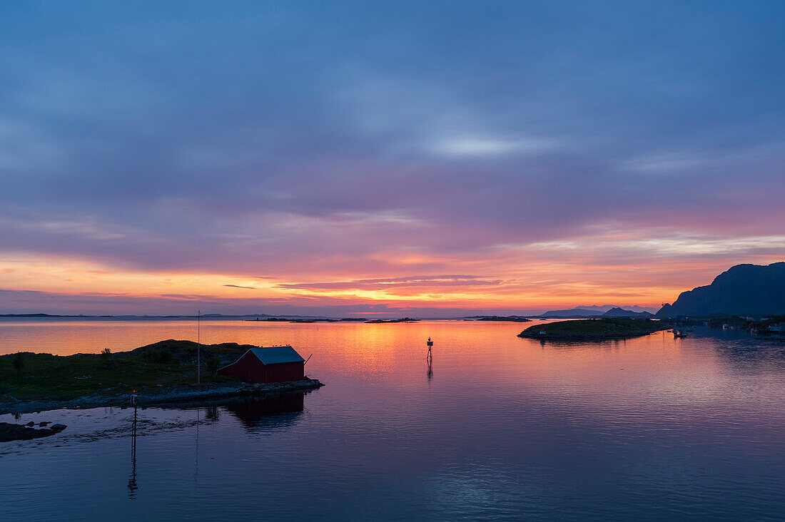 Die Sonne geht hinter silhouettierten Inseln in der Norwegischen See bei Broennoysund unter. Broennoysund, Bronnoy, Norwegen.