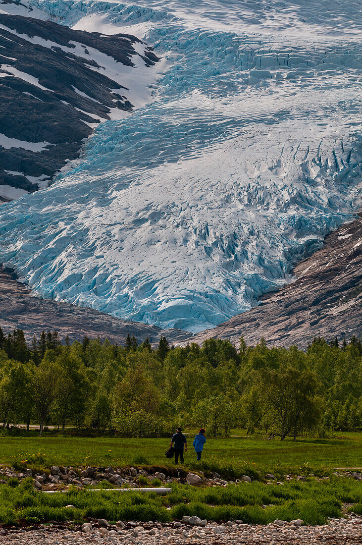 Wanderer genießen ein grünes Tal in der Nähe des Endpunkts des Svartisen-Gletschers. Saltfjellet Svartisen-Nationalpark, Svartisen, Norwegen.