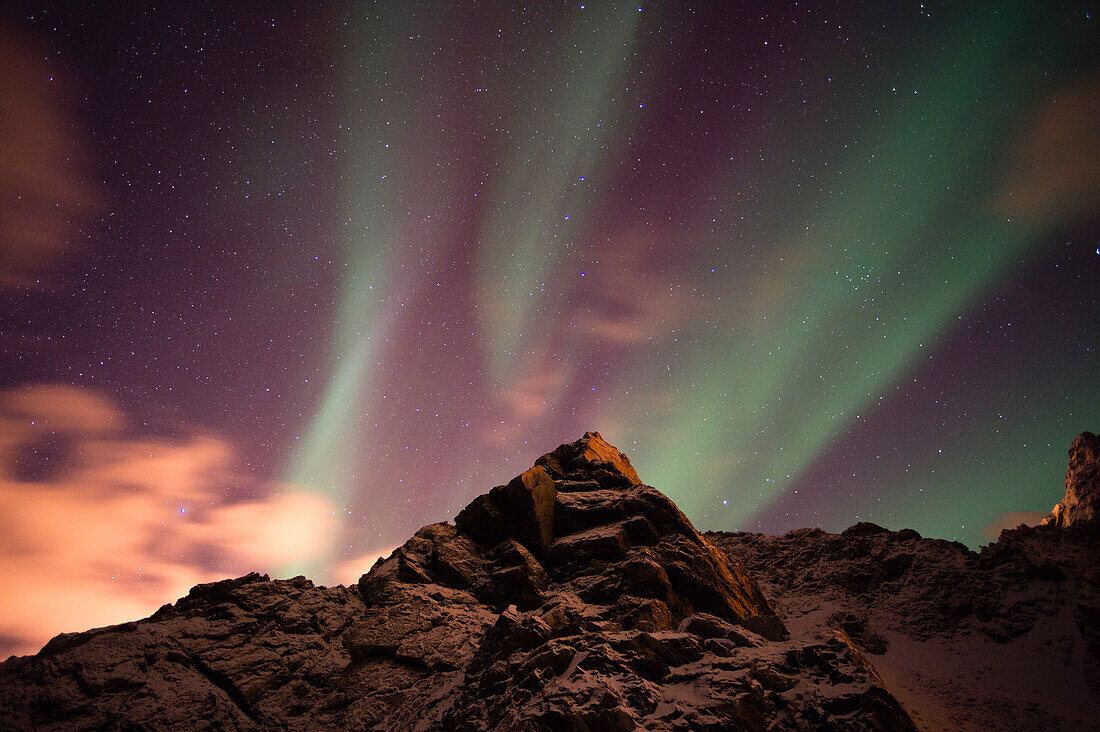 An aurora borealis behind a mountain peak in Andenes. Andenes, Vesteralen Islands, Nordland, Norway.