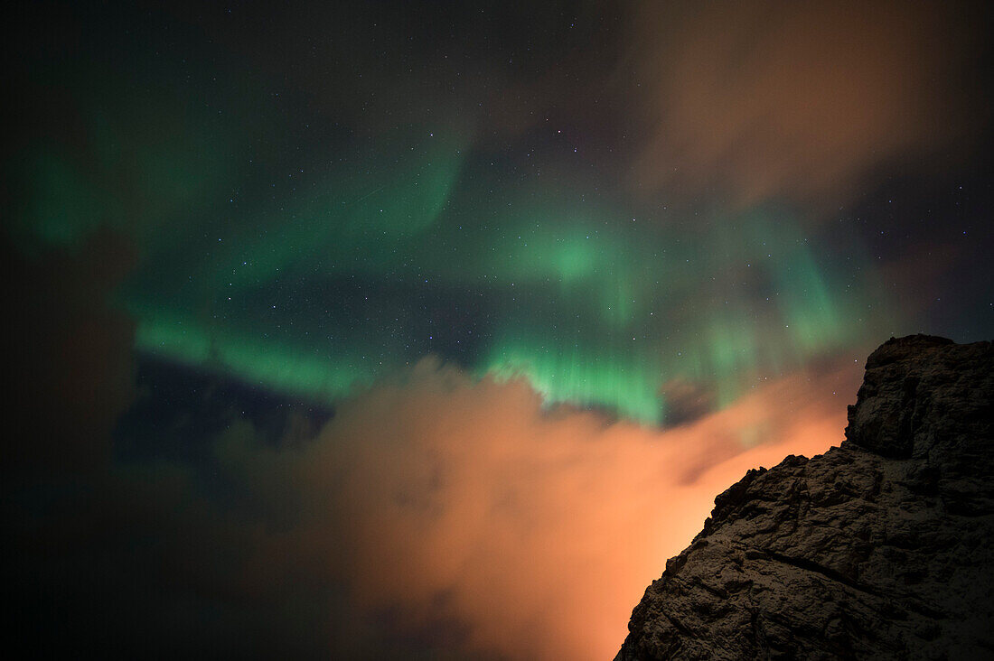 An aurora borealis behind a mountain peak in Andenes. Andenes, Vesteralen Islands, Nordland, Norway.