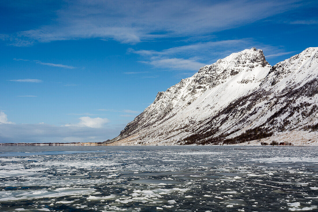 Schneebedeckte Berge und Packeis in der Bucht von Knutstad. Knutstad, Lofoten-Inseln, Nordland, Norwegen.