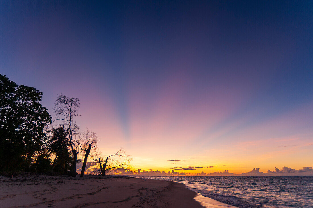 Sonnenstrahlen über einem tropischen Sandstrand bei Sonnenuntergang. Denis Island, Die Republik der Seychellen.