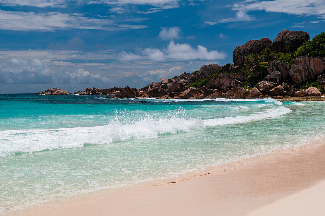 Große Steinfelsen an einem tropischen Strand mit der Brandung des Indischen Ozeans. Grand Anse Beach, Insel La Digue, Republik Seychellen.