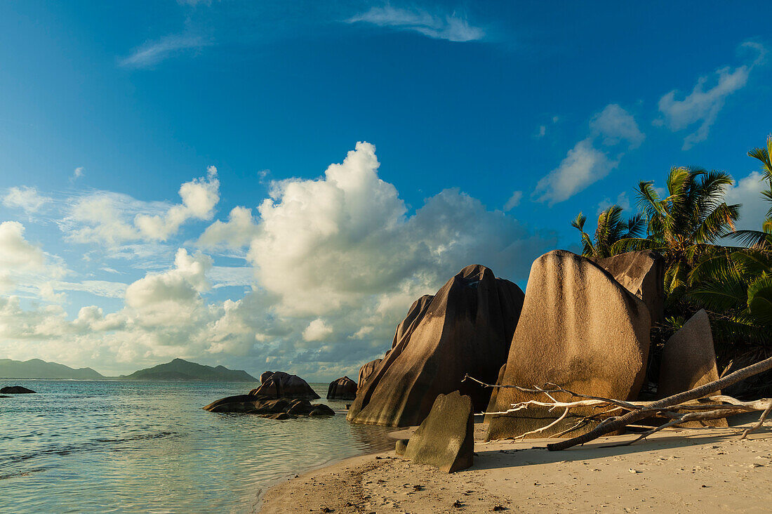 A sandy tropical beach with large boulders and a clear blue sky overhead. Anse Source d'Argent Beach, La Digue Island, The Republic of the Seychelles.