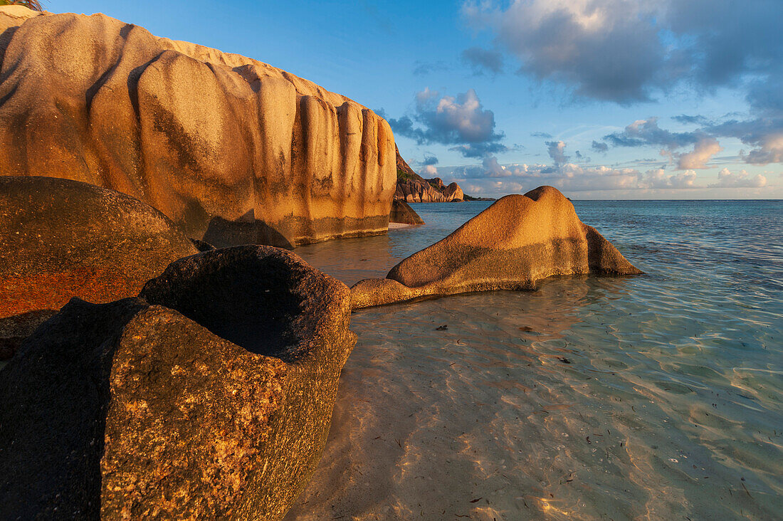 Rock formations on a tropical island beach in warm sunlight at sunset. Anse Source d'Argent Beach, La Digue Island, The Republic of the Seychelles.