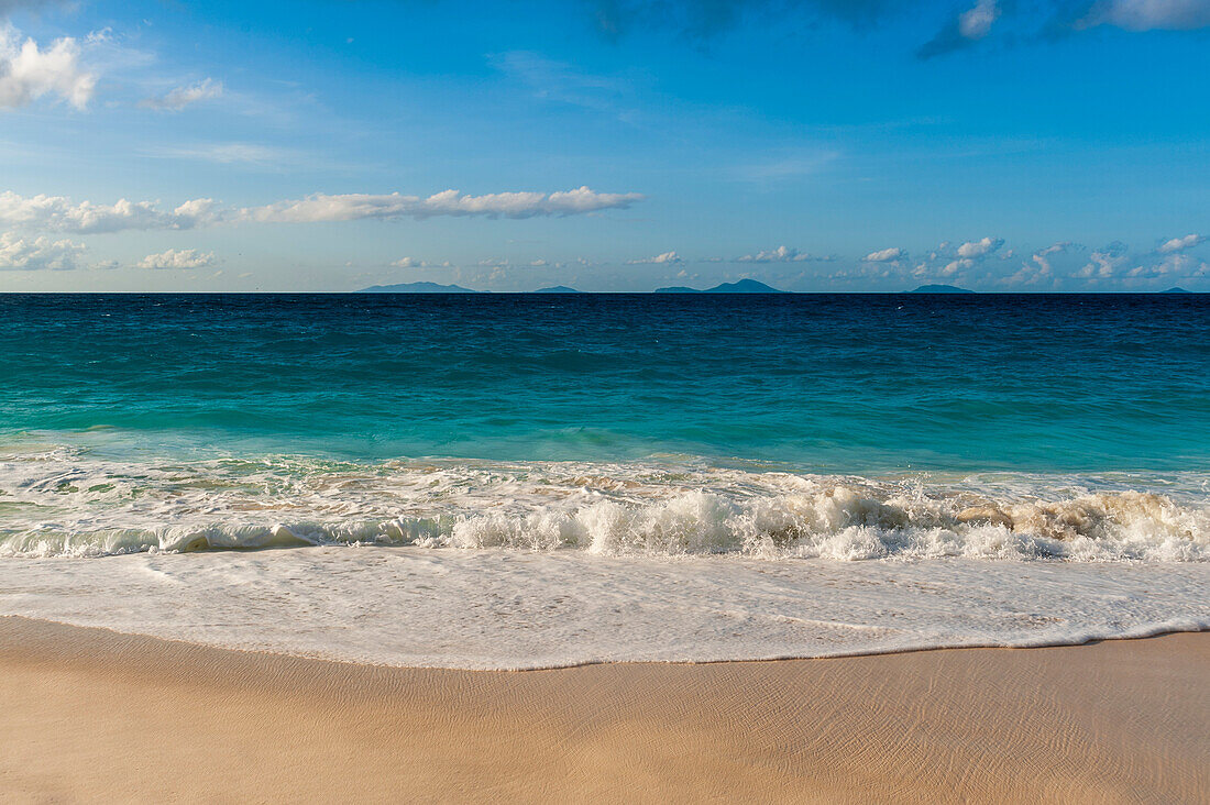 Indian Ocean surf surging onto a sandy tropical beach. Anse Macquereau Beach, Fregate Island, The Republic of the Seychelles.