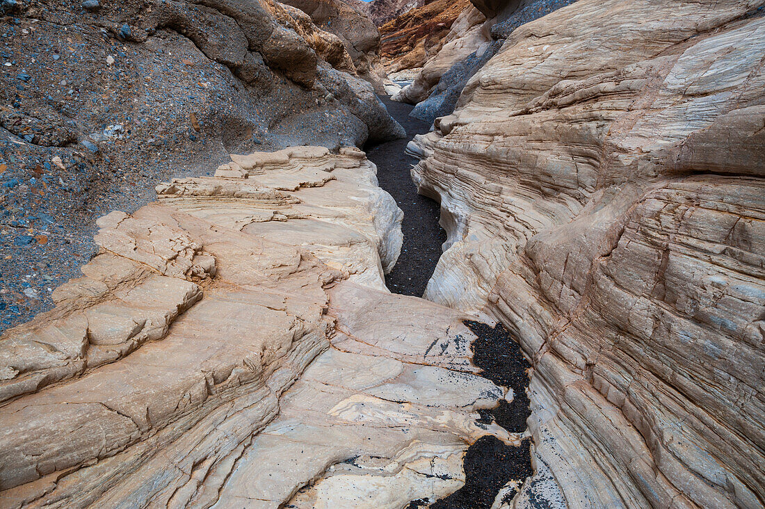 Ein Asphaltweg führt durch die glatten, weiß polierten Marmorwände im Mosaic Canyon. Death-Valley-Nationalpark, Kalifornien, USA.