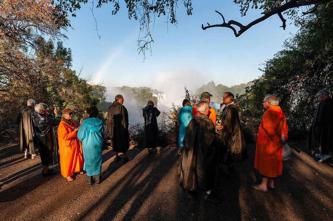 Tourist in raincoats enjoying Victoria Falls. Victoria Falls National Park, Zimbabwe.