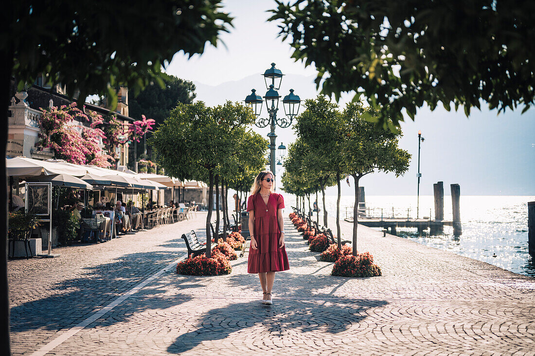 Blonde girl with red dress walking in Gargnano, a small village on Garda Lake, Brescia province, Lombardy, Italy